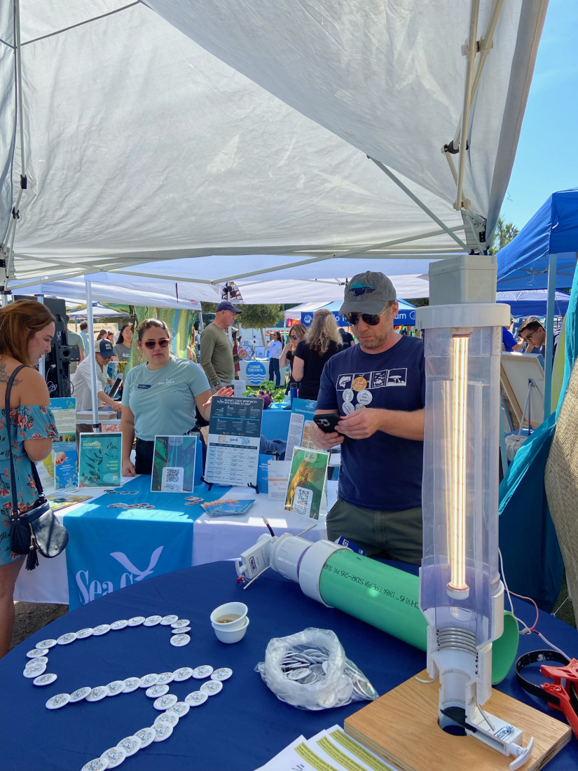 Project team member Dan Gossard pictured with a CLASH system prototype on a display table at California Seaweed Festival in 2023. 