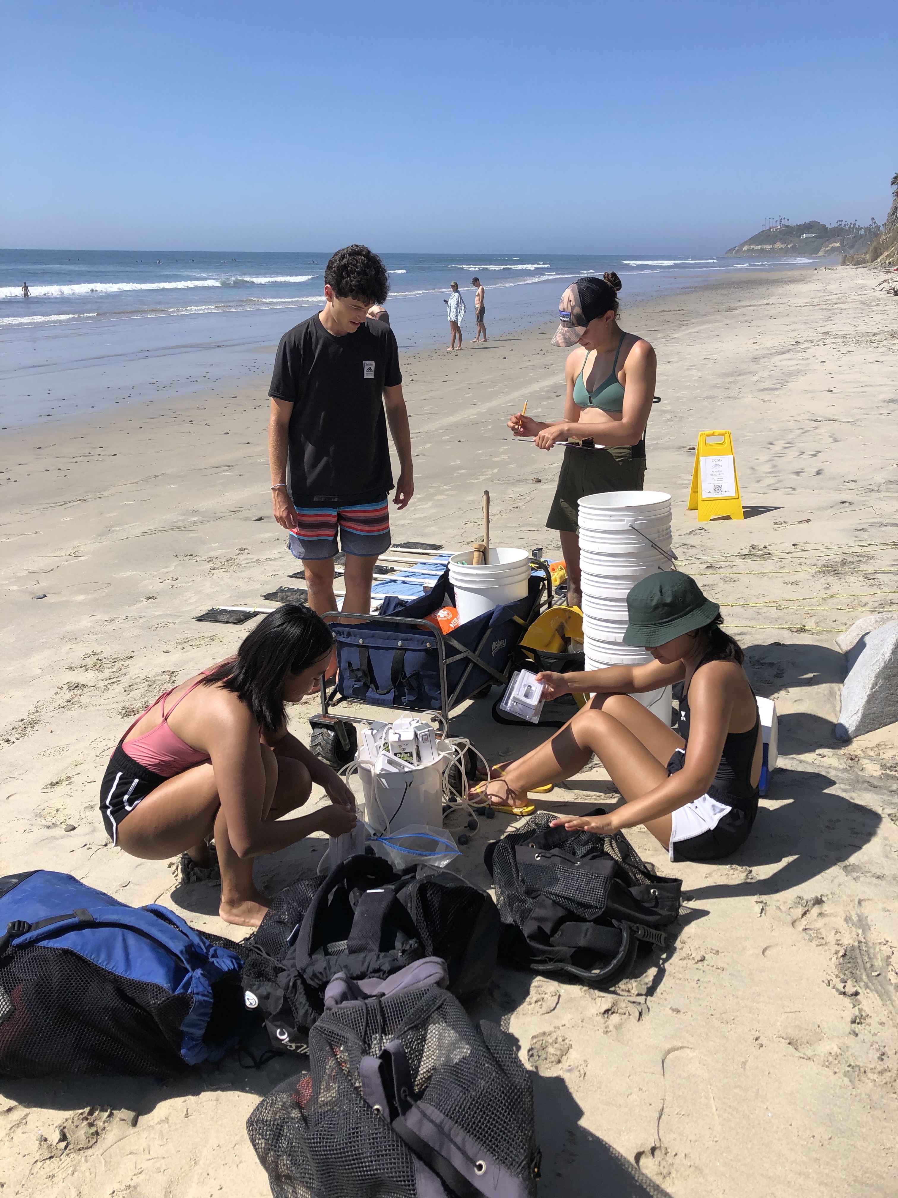 The team organizes tools and equipment for the beach survey.