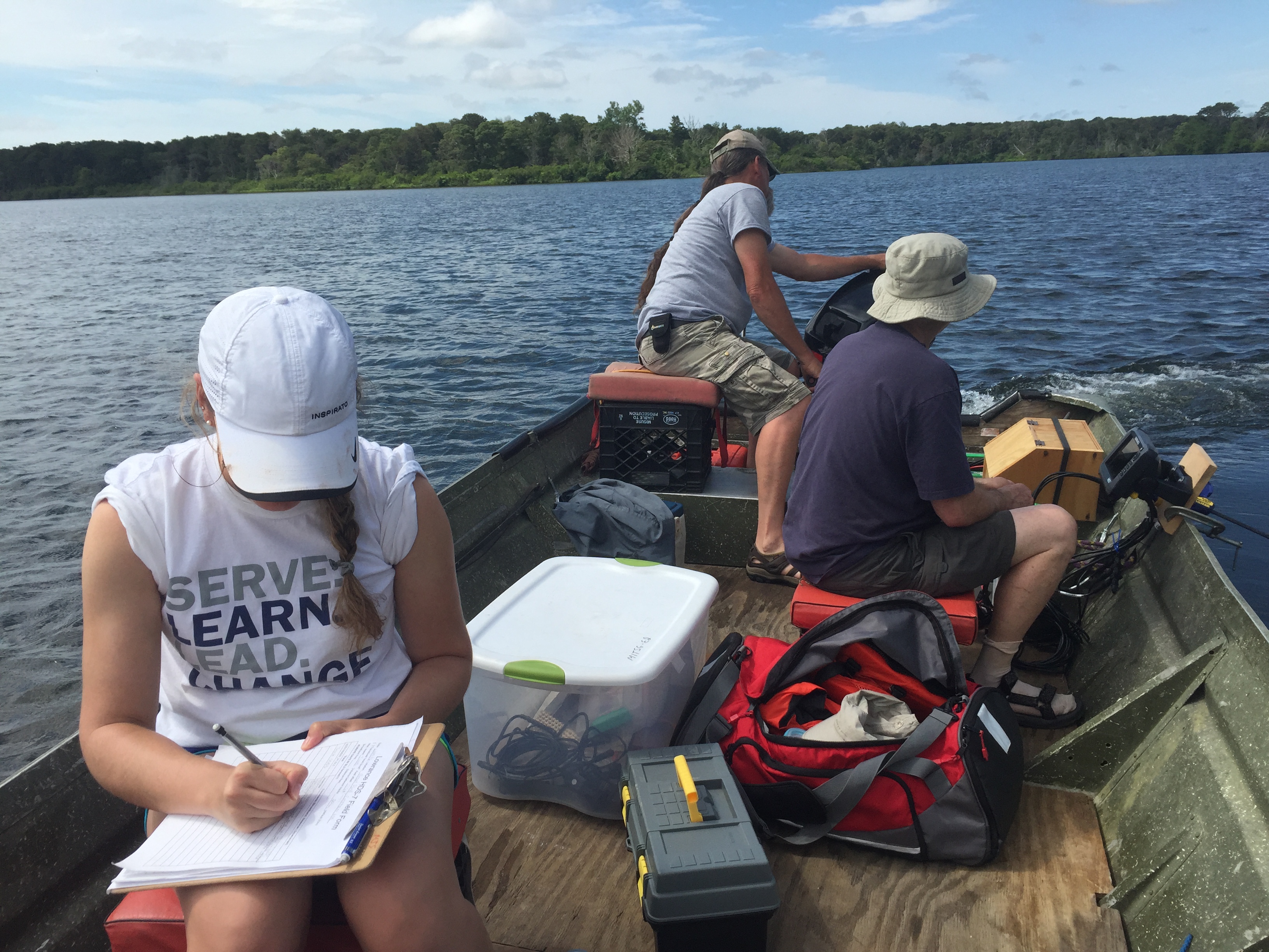 three volunteers on a boat in the water with equipment