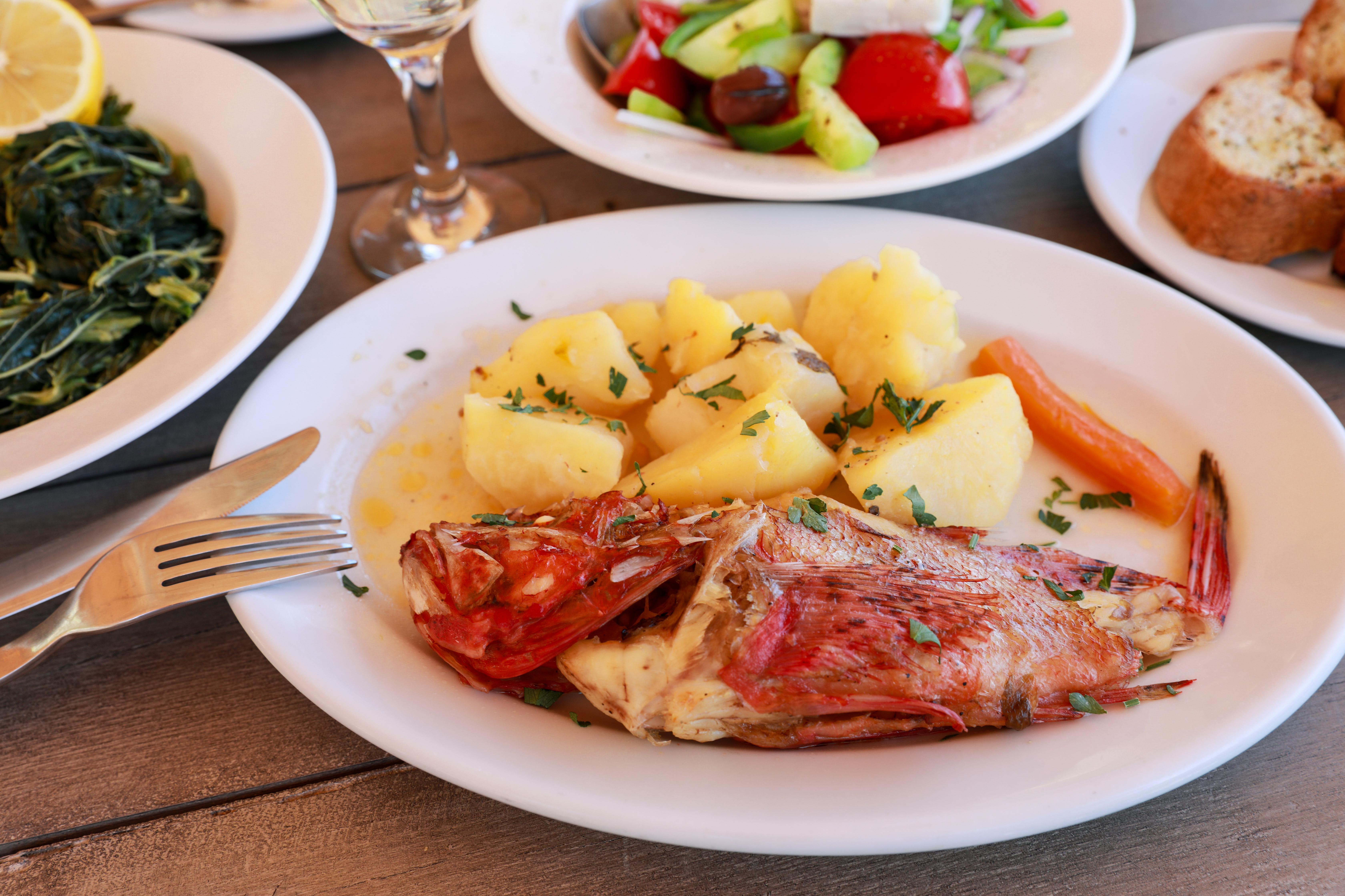 Victoria Kurylo/shutterstock red scorpionfish with potatoes and plates of vegetables and bread