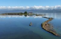 Flooded landscape with one house sitting on a small remaining sliver of land