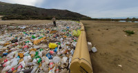 Man observing debris captured by trash booms in a sediment basins