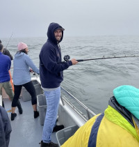 Ben Dorfman standing at the railing of a boat with a fishing rod