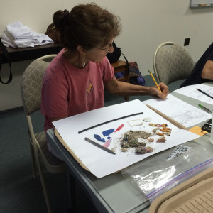 woman recording information on paper with sand and debris on the table in front