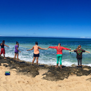 people standing on the coastline with their arms raised to the side