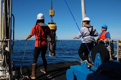 Researchers stand on a boat deck raising a remotely operated vehicle out of the water