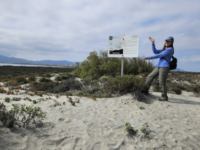 Meliza Le in front of a sign explaining the importance of dunes