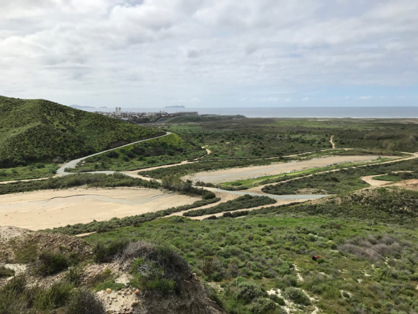 Tijuana in the distance, and sediment basins with trash booms in the foreground.
