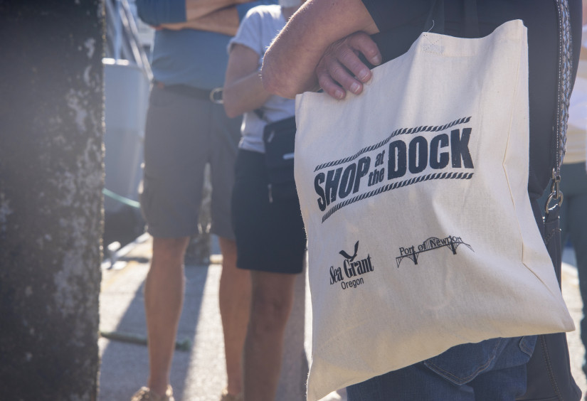 A participant in one of Oregon Sea Grant's Shop at the Dock tours in Newport shoulders a branded tote bag