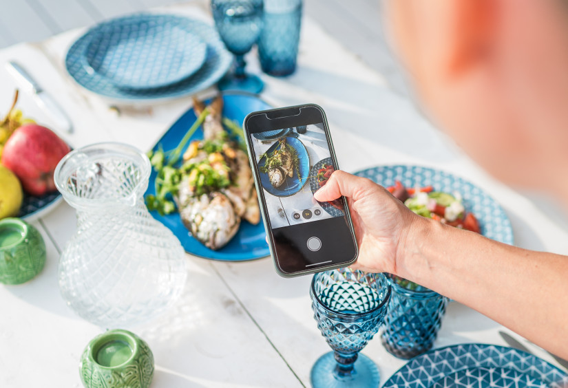 person taking picture of fish dish on their iphone