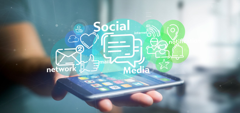 phone in hand with graphics above depicting social media icons