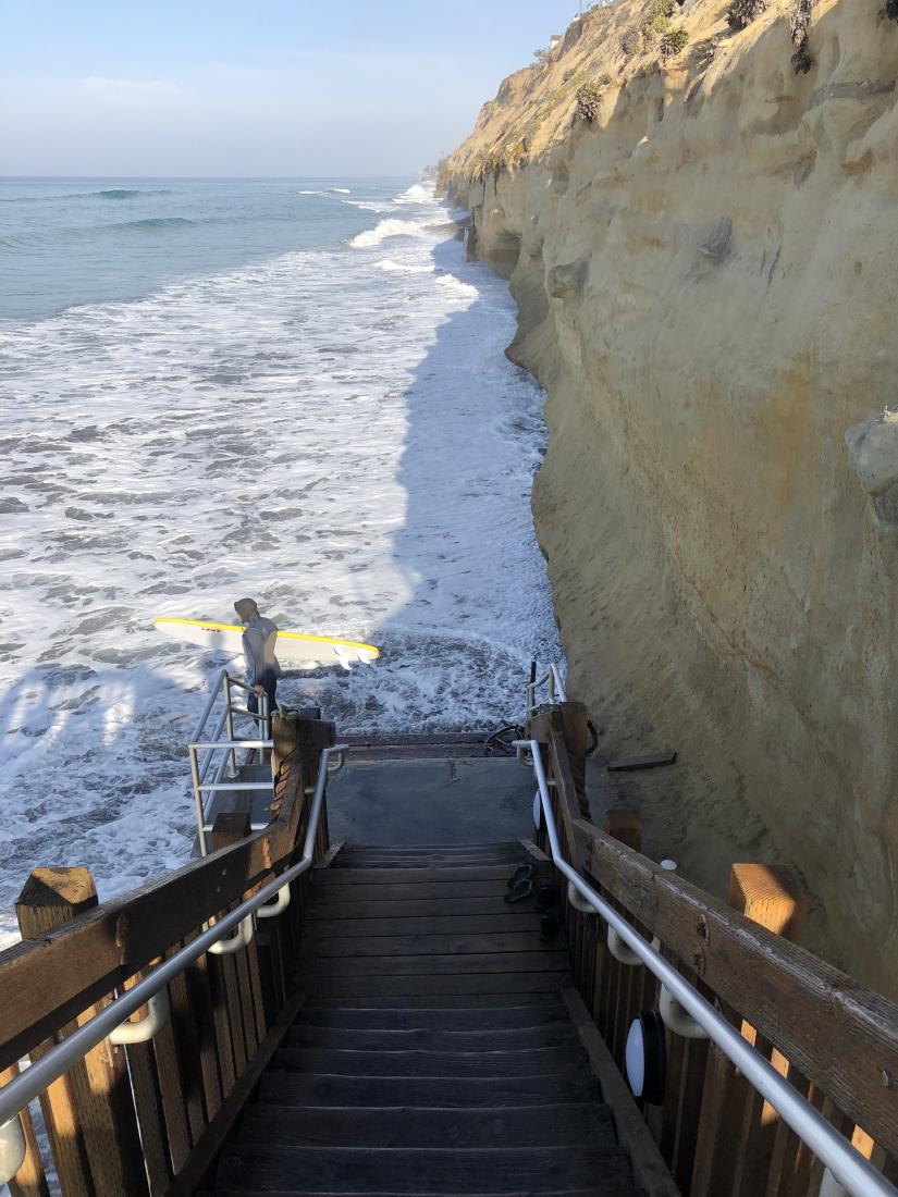 Stairs going down to a flooded beach.