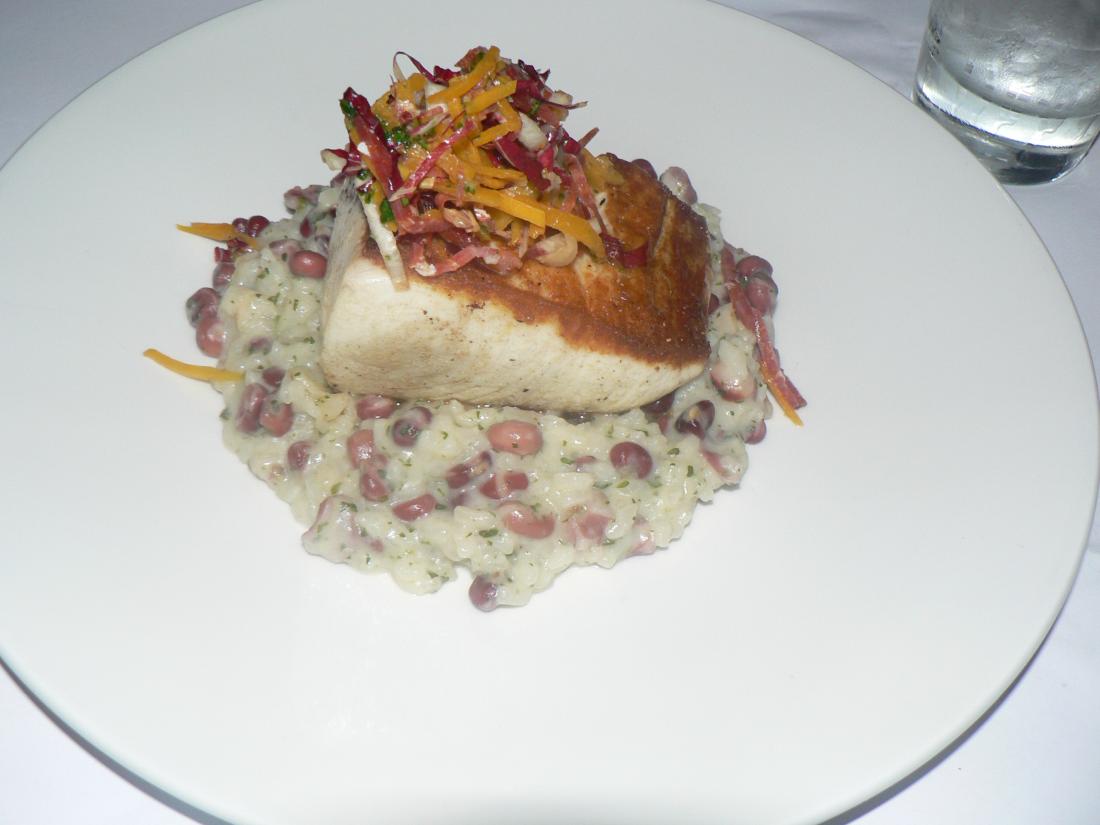 cooked wahoo on top of a bed of rice and beans with garnish