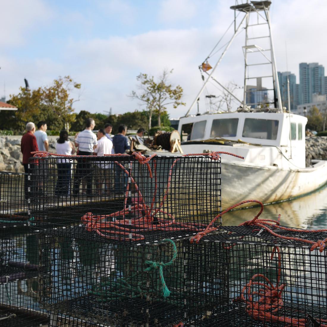 People on dock next to fishing boat with traps.