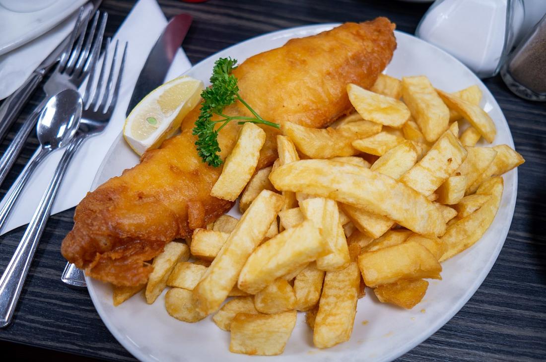 Fish and chips with parsley garnish and lemon wedge.