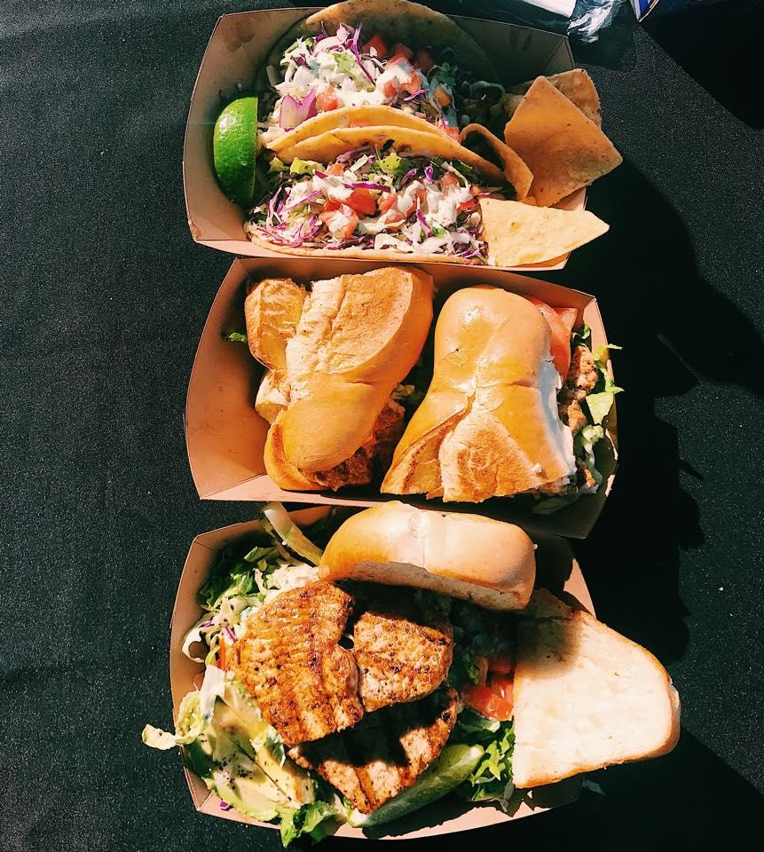 Fish tacos and fish sandwiches in paper trays.