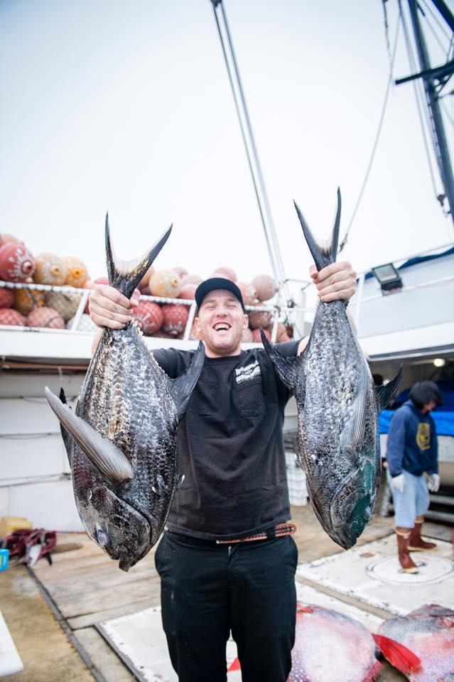 fisherman holding two sickle pomfrets