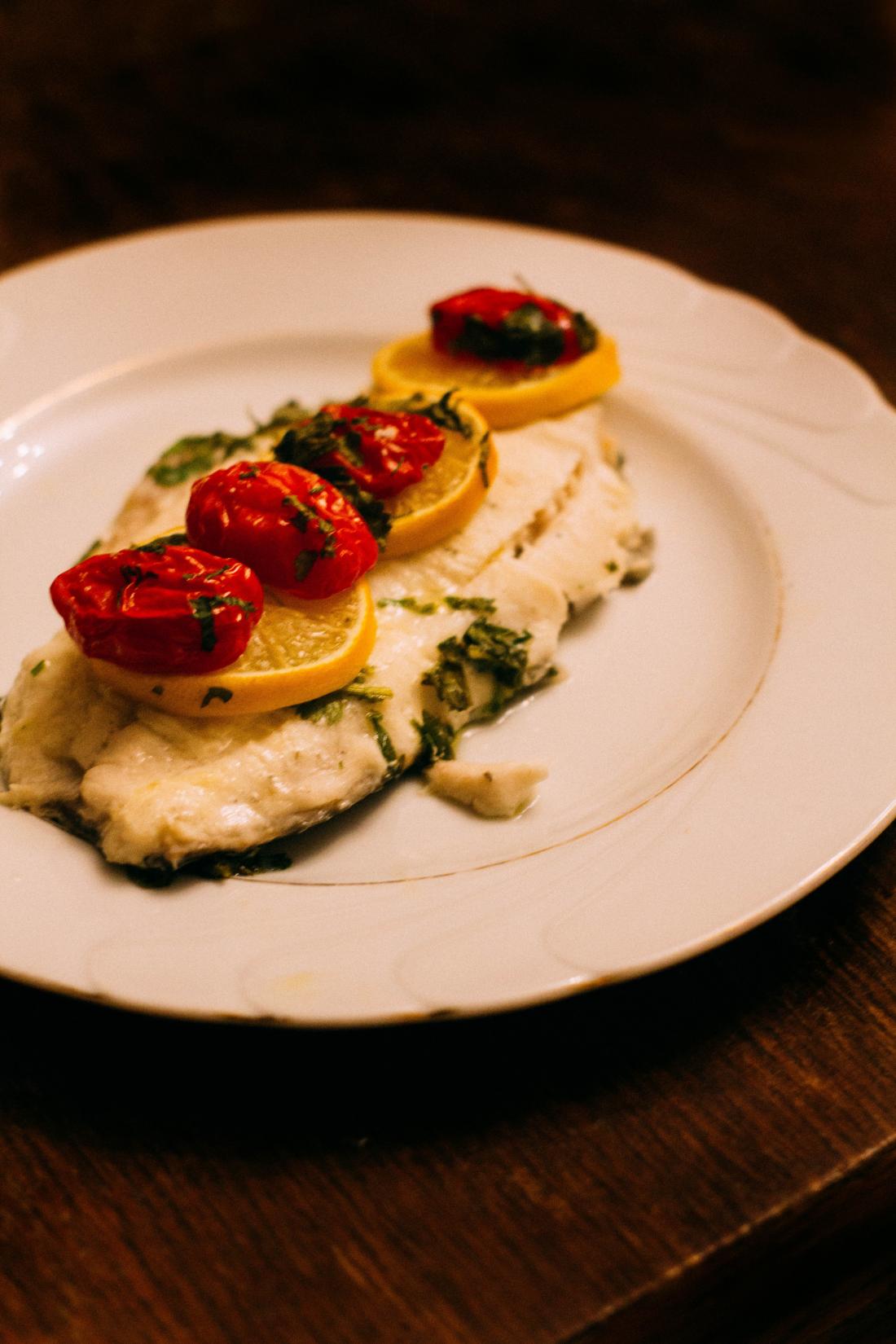 Whitefish filet topped with lemon and cherry tomatoes.