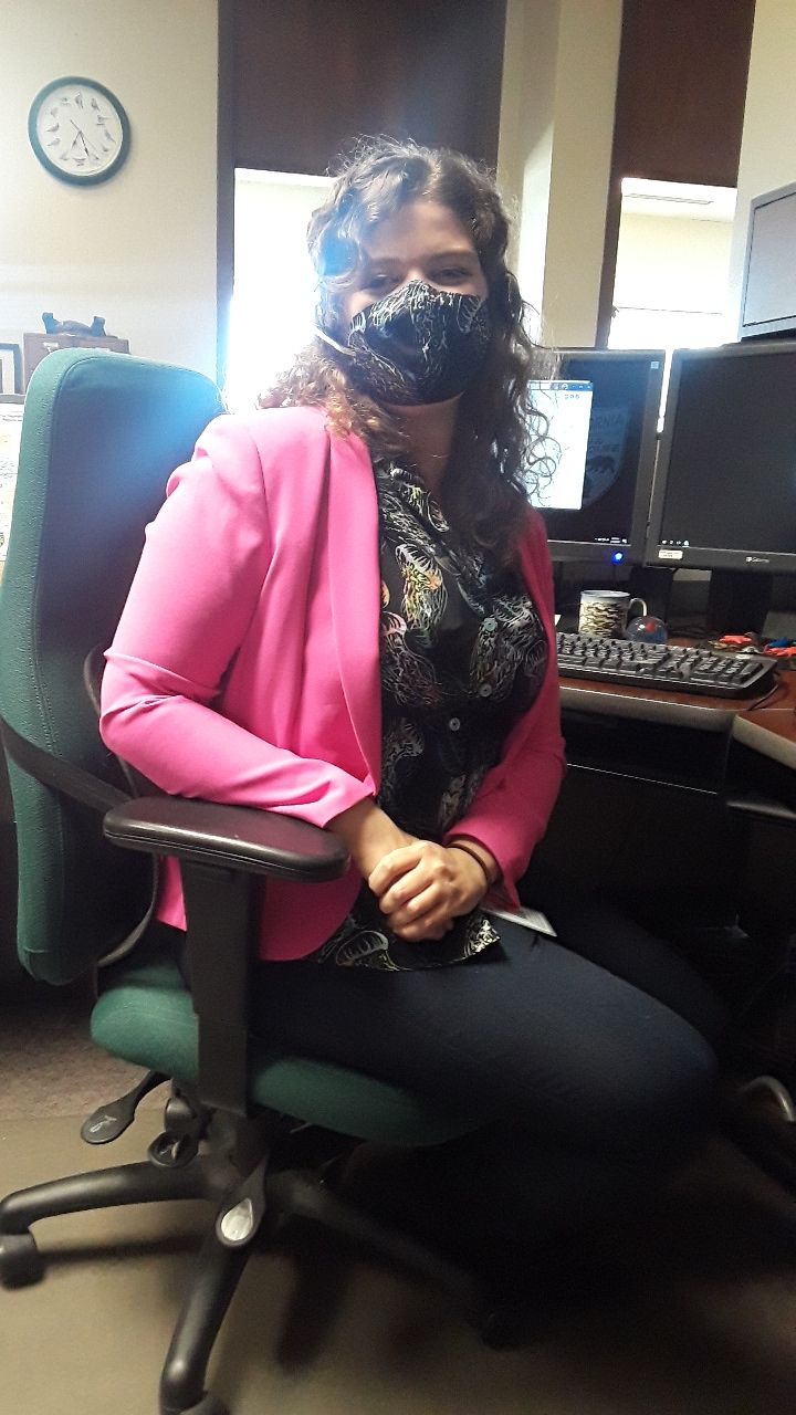 Rose Dodgen, sitting at her office desk wearing a face mask